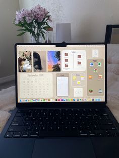 an open laptop computer sitting on top of a bed next to a vase with flowers