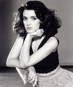 black and white photograph of a woman with her hand on her chin holding a purse