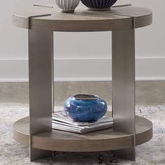 a blue vase sitting on top of a wooden table next to a magazine rack with magazines