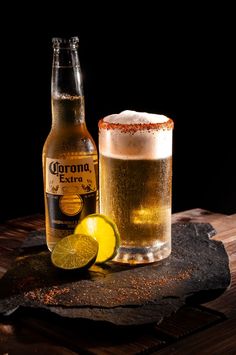 a bottle of corona beer next to a glass with a lime slice on the side