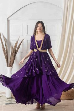 Strut around in this contemporary style indo-western dress in deep amethyst hue with contrasting golden handwork. Designed with eye-catching floral motifs and a wrapped silhouette, this dress has the required sophistication and charm. With a deep V neck and knotted appeal, style it with layered necklace and earrings for an event-ready ensemble you'll adore.Style Wrap style dress Knotted closure Ankle length style Embroidered lace detailing All over motif embroidery Decadent amethyst color George Purple Party Kurta For Navratri, Purple Dress With Dabka Work For Reception, Purple Reception Dress With Dabka Work, Purple Floor-length Festive Dress, Purple Kurta For Party Festivals, Front Open Dress With Zari Work For Reception, Purple Zari Work Dress For Reception, Formal Purple Lehenga With Zari Work, Purple Anarkali Dress With Resham Embroidery