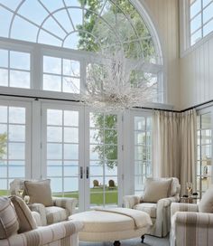 a large living room with white furniture and windows overlooking the water in front of it