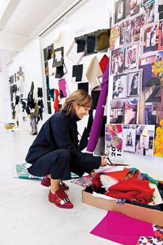 a woman kneeling down in front of a box filled with clothes and other clothing items