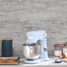 a blue mixer sitting on top of a counter next to other kitchen supplies and utensils