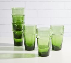 five green glasses sitting on top of a white table