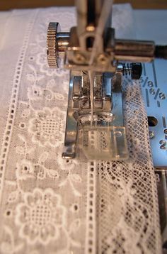 the sewing machine is on top of the table with white doily and laces