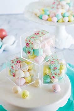 three clear boxes filled with marshmallows sitting on top of a cake plate