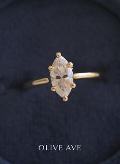 an engagement ring with a pear shaped diamond on it's side and the words olive ave written in gold