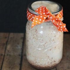 a mason jar filled with white and orange colored stuff on top of a wooden table