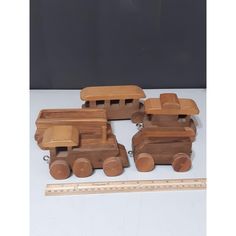 three wooden toy trucks are next to a ruler