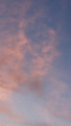 the airplane is flying high in the sky at sunset or dawn, with pink clouds behind it