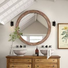 a bathroom with two sinks and a round mirror on the wall above it's vanity