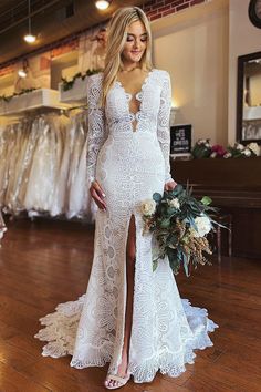 a woman in a white wedding dress standing on a wooden floor holding a bouquet and looking at the camera