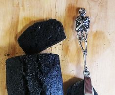 a piece of cake next to a knife on a wooden table with a skeleton keychain