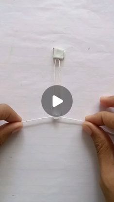 two hands holding an electronic device in front of a white sheet of paper with the video below it