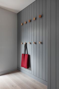 a red bag is hanging on the wall next to a coat rack with wooden pegs