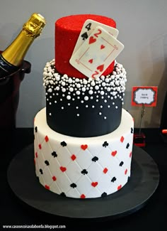 a three tiered cake decorated with playing cards and a bottle of champagne on top