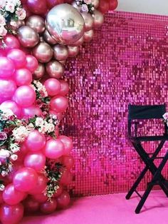 a chair and some balloons in front of a pink wall with sequins on it