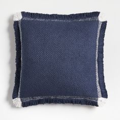 a blue pillow with white fringes on the edges and a dark blue cushion cover