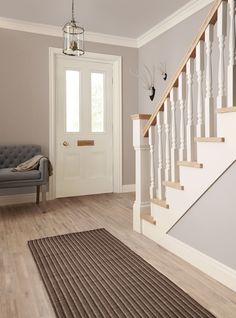 a living room with a gray door and white stair case next to a grey chair