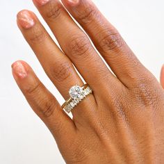 a woman's hand with a diamond ring on top of her finger and the other hand holding an engagement ring