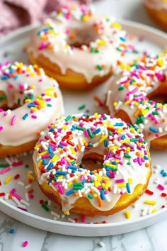 there are many donuts with white frosting and sprinkles on the plate