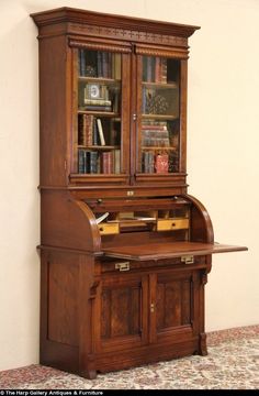 an old wooden desk with bookshelves and drawers on the top, in front of a wall