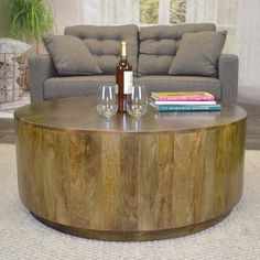 a wooden table with two wine glasses on it in front of a couch and coffee table