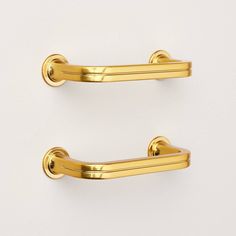 two gold - plated handles on white wall, one is open and the other has closed