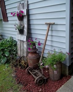 an old wheelbarrow with flowers in it next to a building and some plants