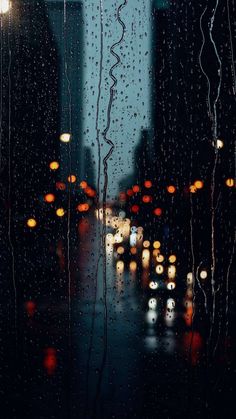 rain is pouring down on the window and cars are driving in the street at night