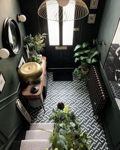 a bathroom with green walls, black and white tile flooring and plants in the corner