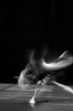 a blurry photo of a man playing tennis in the dark with his racquet