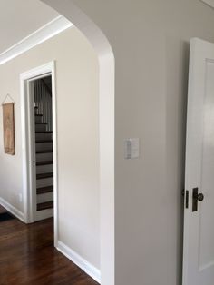 an open door leading to another room in a house with white walls and wood floors