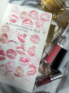 a book with lipstick on top of it next to other cosmetics and makeup products,