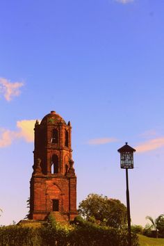 an old brick tower with a clock on the side and a light pole next to it