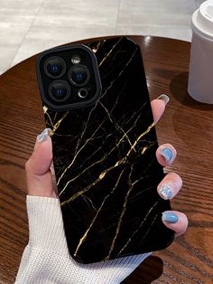 a woman's hand holding up a black marble phone case