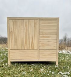 a wooden cabinet sitting on top of a grass covered field