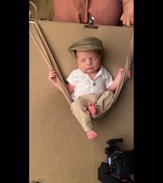 a baby is laying in a hammock and wearing a hat