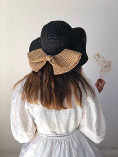 the back of a woman's head wearing a black hat with a gold bow