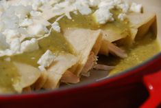 tortilla shells covered in green sauce and shredded cheese on top, sitting in a red pot