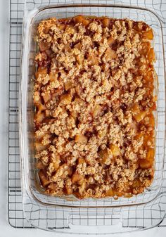 a casserole dish filled with fruit and crumbled toppings on a cooling rack