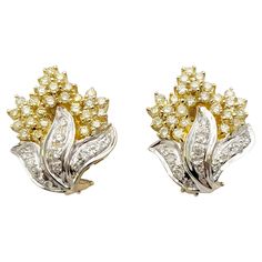 These super sparkly diamond cluster earrings absolutely glow. The elegant two toned design pops beautifully on the lobe, giving a chic and glamorous look. These beautiful earrings each feature shimmering clusters of white and fancy light yellow diamonds in a half flame motif. The bottom half of the pair are filled with natural white pave diamonds (H-I / SI) set in polished 14 karat white gold 'flames'. The white gold setting brightens up the icy white stones and makes them really pop. Above the flames sit a cluster of fancy light yellow diamonds set in polished 14 karat yellow gold, enhancing the subtle warmth of the natural stones and making them glow. A post and lever-back closure hugs the lobe for a secure fit. These earrings are in very good estate condition and have been professionall Fancy Yellow Diamond Earrings, Luxury Yellow Drop Earrings, Luxury Yellow Diamond Earrings, Yellow Diamond Cut Fine Jewelry Earrings, Light Yellow Diamond, Elegant Yellow Diamond-cut Earrings, Fancy Light, Diamond Cluster Earrings, Flame Design