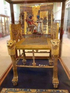 an ancient chair with two lions on it in a museum display case next to a rug