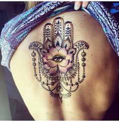 a woman's back with a hamsa tattoo on her shoulder and an eye in the center