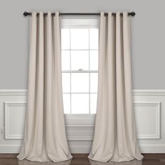 a white curtain hanging on the side of a window in a room with hardwood floors