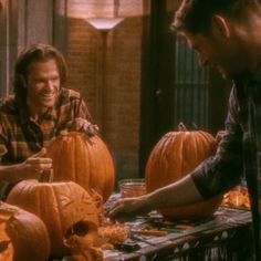 two men are carving pumpkins for halloween