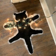 a black cat with christmas lights on it's back laying on the floor in front of a door