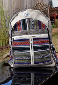 a multicolored backpack sitting on top of a table next to a wooden fence