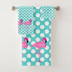 a towel with pink flamingos and white polka dots hanging on a hook in front of a wall